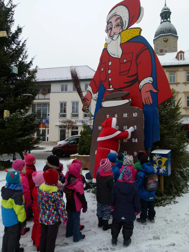 Weihnachtsmann empfängt Kinder am Kalender in Schmölln | Der Weihnachtsmann öffnet für einre Kindergruppe das Türchen am
großen Adventskalender.