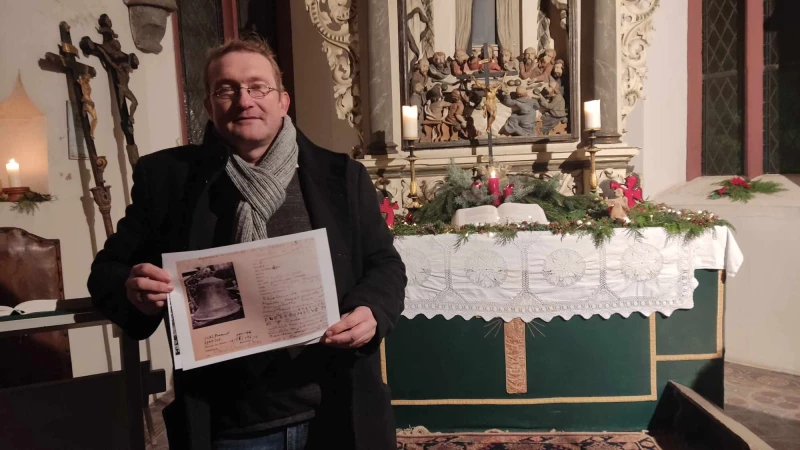 Den Advent in Zürchau eingeläutet | Jörg Hahnel mit der Kopie einer Karteikarte zu einer Glocke, die auf dem Hamburger Glockenfriedhof landete.